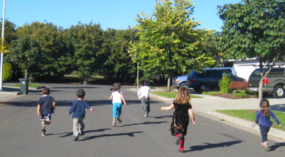 Kids running down the sidewalk on a sunny day
