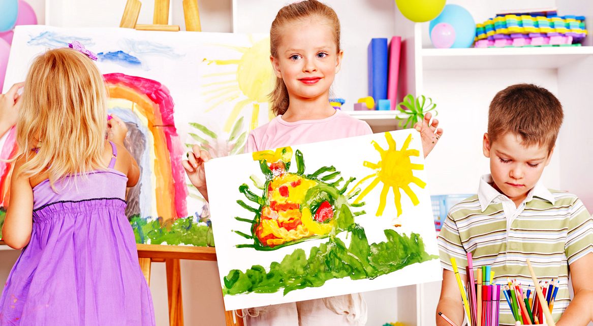 Preschoolers proudly holding up their paintings