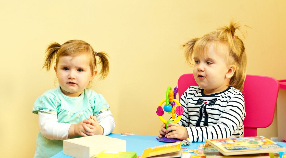Two toddlers playing with toys at a table