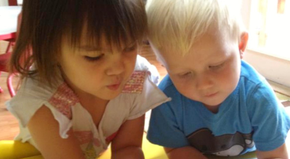 Two Little VIP toddlers looking at a picture book together
